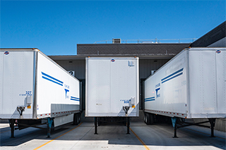 Camiones semirremolque estacionados en un almacén para carga y descarga.