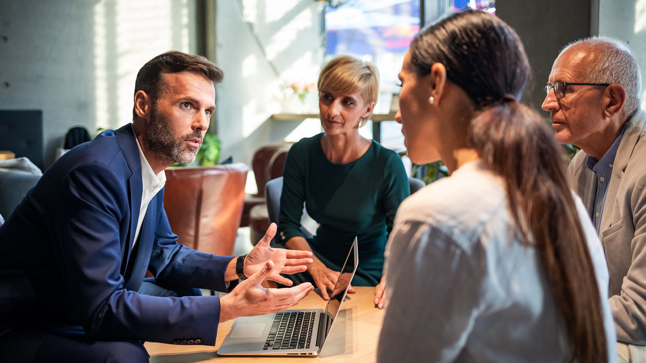 Four business people using Minitab's project charters to manage and organize their project in a cafe.